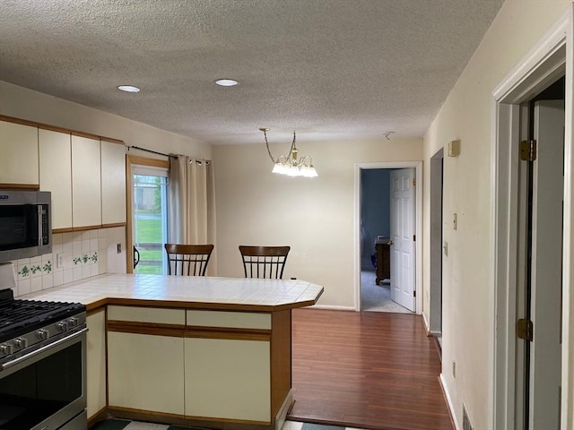 14 Plain Rd E Unit B, Deerfield, MA 01373 - kitchen with stainless steel appliances, a peninsula, tile counters, decorative backsplash, and dark wood finished floors