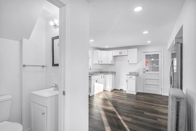 kitchen with dark wood-type flooring, radiator, white cabinets, sink, and stainless steel dishwasher