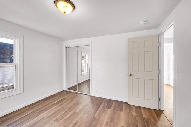 unfurnished bedroom with wood-type flooring, multiple windows, and a closet