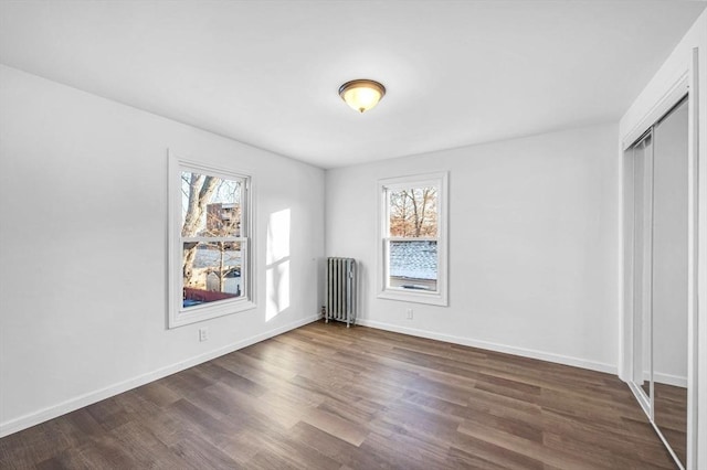 unfurnished bedroom with radiator, a closet, and dark hardwood / wood-style flooring