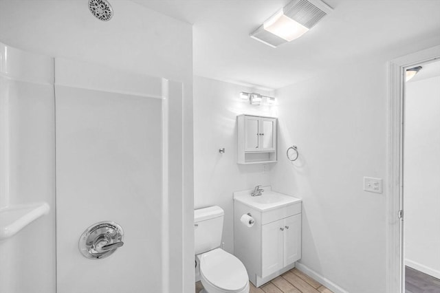 bathroom featuring a shower, hardwood / wood-style floors, vanity, and toilet