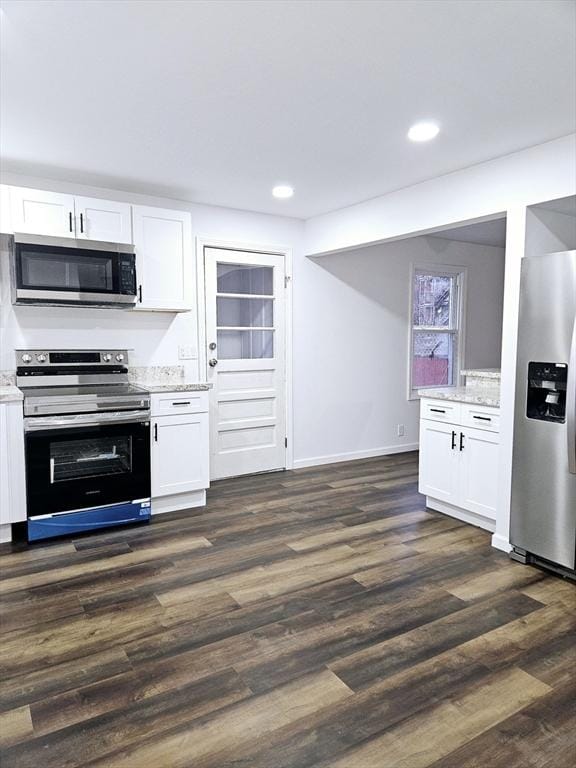 kitchen with white cabinets, appliances with stainless steel finishes, dark hardwood / wood-style floors, and light stone counters