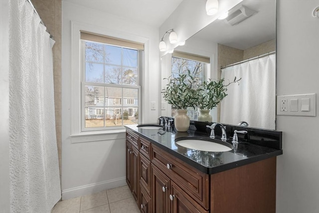 bathroom with double vanity, a sink, baseboards, and tile patterned floors