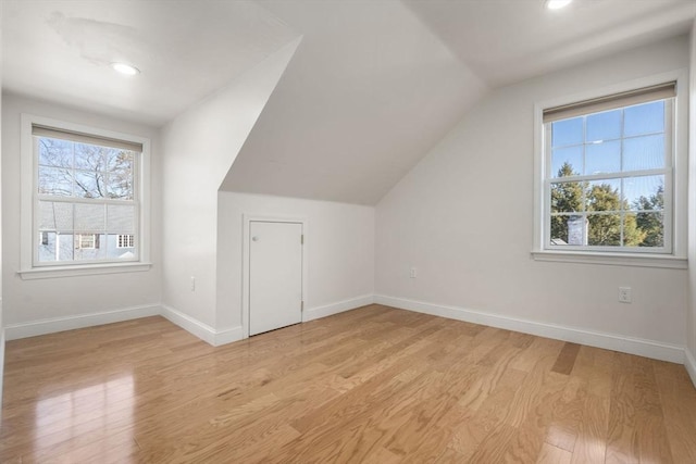 additional living space featuring lofted ceiling, light wood finished floors, plenty of natural light, and baseboards