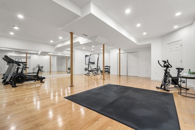 exercise area featuring baseboards, visible vents, wood finished floors, and recessed lighting