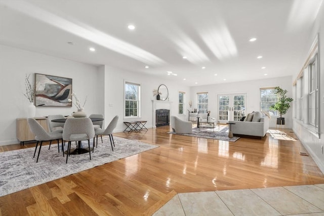 living area with plenty of natural light, a fireplace, wood finished floors, and french doors