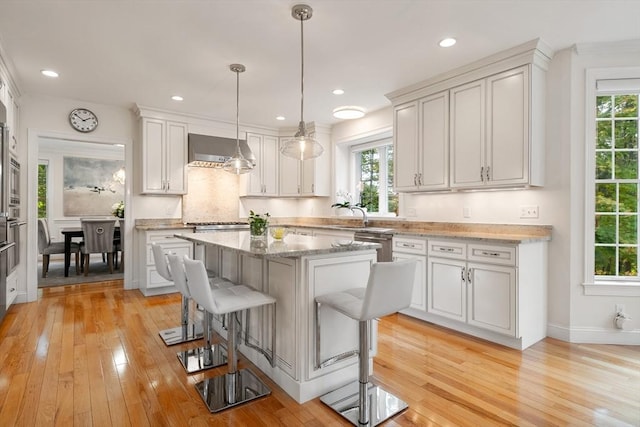 kitchen with light wood-type flooring, white cabinetry, and a kitchen island