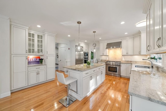 kitchen featuring a center island, wall chimney exhaust hood, decorative light fixtures, light hardwood / wood-style floors, and stainless steel appliances