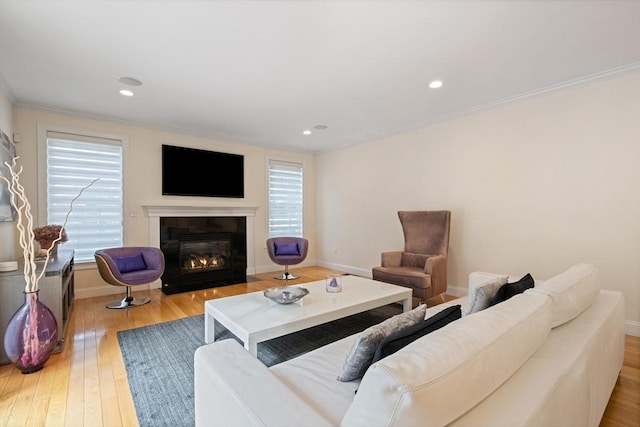 living room featuring crown molding, a wealth of natural light, and light hardwood / wood-style flooring