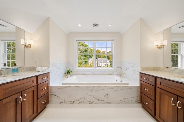 bathroom with plenty of natural light, vanity, and tiled bath