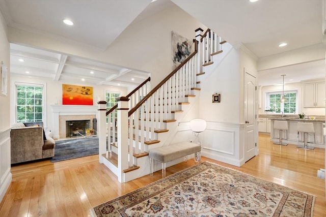 stairs with wood-type flooring, plenty of natural light, and coffered ceiling