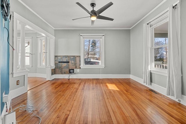 unfurnished living room featuring light wood-type flooring, a fireplace, ornamental molding, and a wealth of natural light