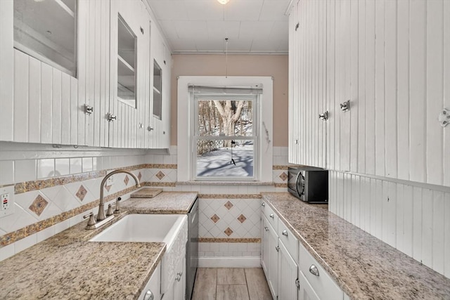 kitchen featuring glass insert cabinets, black microwave, white cabinetry, and a wainscoted wall