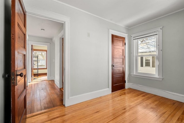 unfurnished room featuring light wood-type flooring, baseboards, and ornamental molding