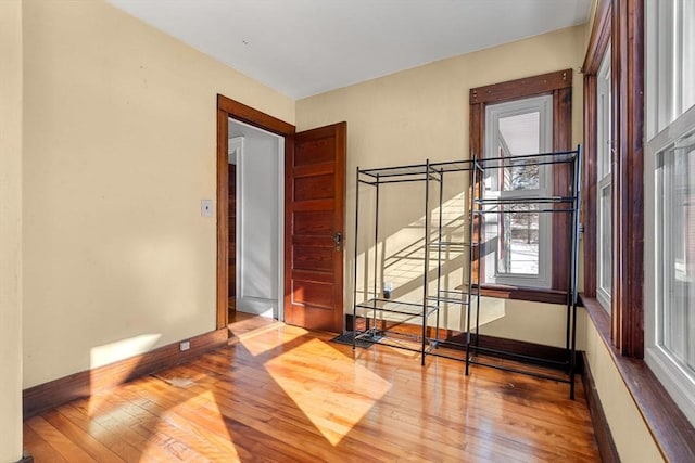 empty room with wood-type flooring, stairs, and baseboards