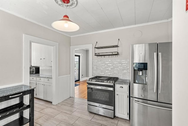 kitchen featuring a wainscoted wall, stainless steel appliances, white cabinetry, light stone countertops, and crown molding