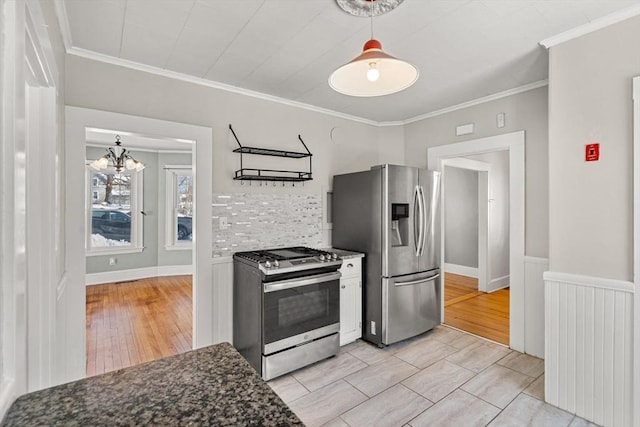 kitchen featuring stainless steel appliances, dark stone counters, light wood finished floors, decorative light fixtures, and crown molding