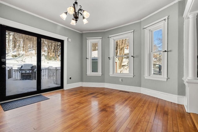 doorway to outside with wood-type flooring, baseboards, crown molding, and ornate columns