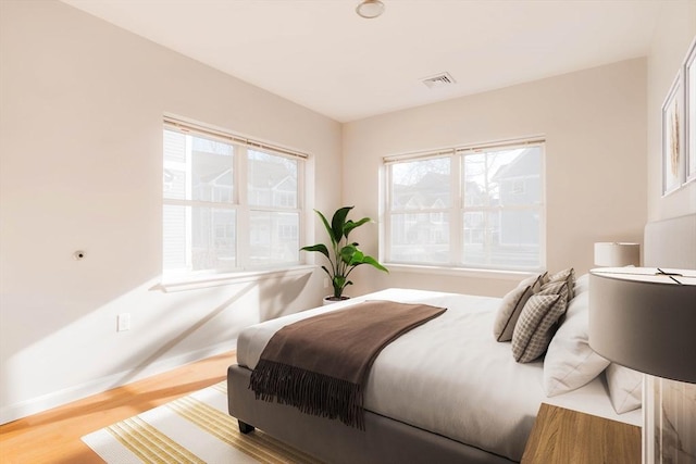 bedroom with visible vents, baseboards, and wood finished floors