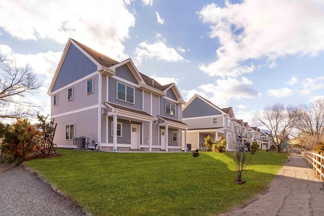 view of front of property with a front yard, a residential view, and central AC