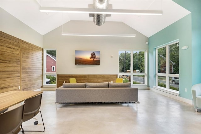 living area with concrete flooring and high vaulted ceiling