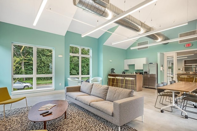 living area with finished concrete floors, a high ceiling, and visible vents