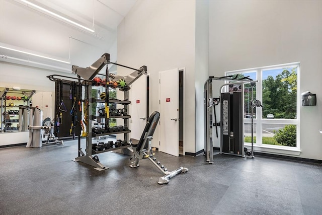 exercise room with a high ceiling and baseboards