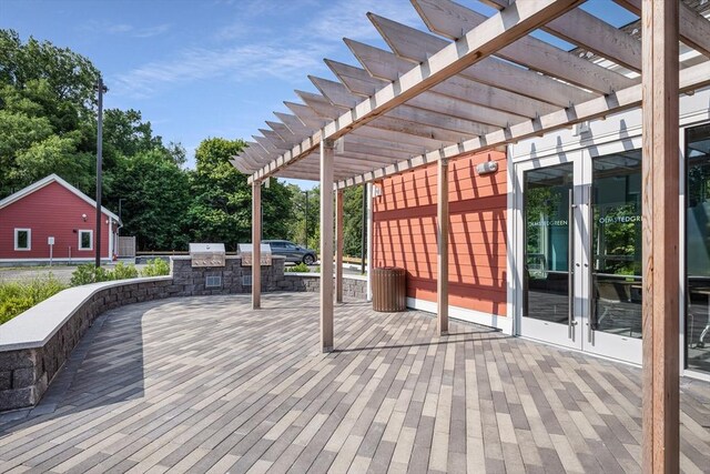 deck featuring a grill, french doors, a pergola, and an outdoor kitchen