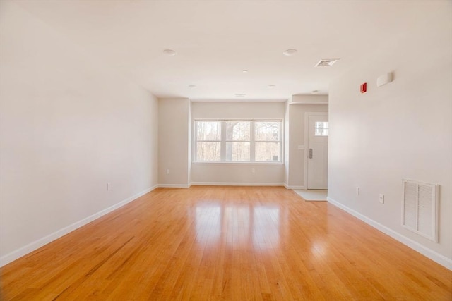 unfurnished room featuring visible vents, light wood-style flooring, and baseboards