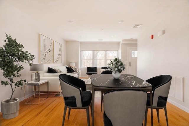 dining room with light wood-type flooring, visible vents, and baseboards