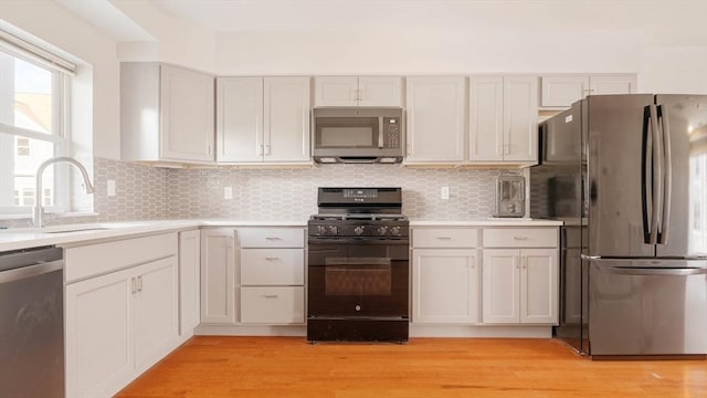 kitchen featuring backsplash, stainless steel appliances, light countertops, and a sink