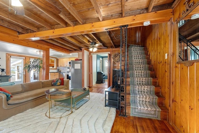 living area with wood walls, light wood-type flooring, ceiling fan, beamed ceiling, and wood ceiling