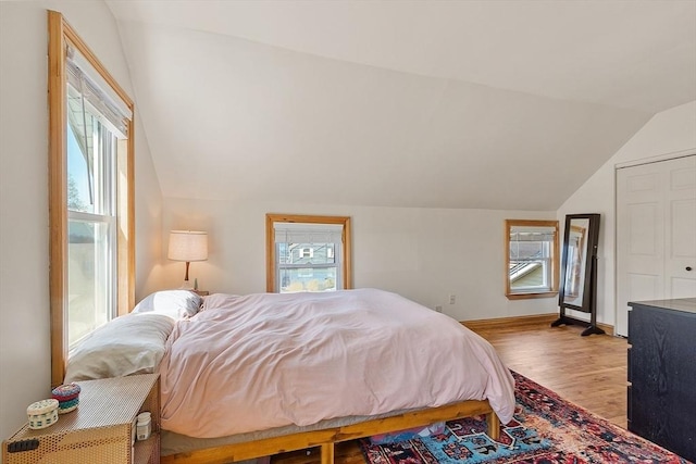 bedroom with baseboards, wood finished floors, and vaulted ceiling