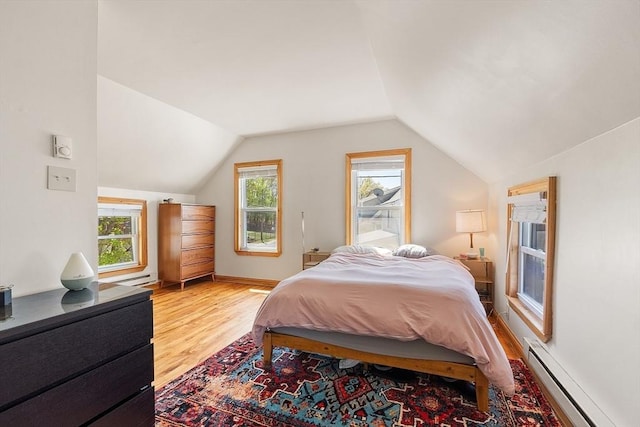 bedroom with lofted ceiling, baseboard heating, and wood finished floors