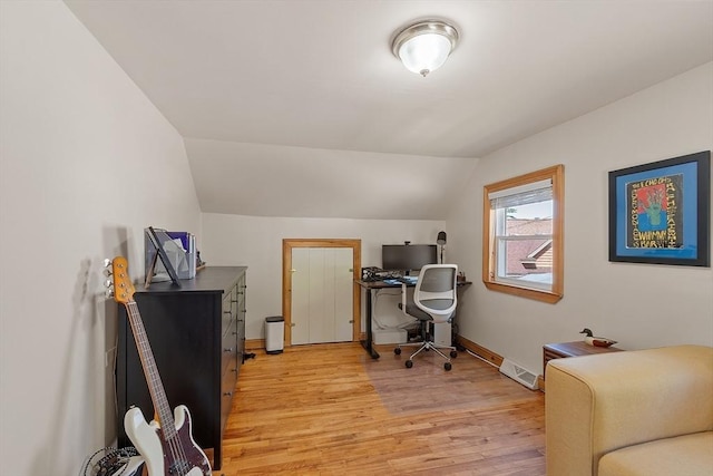 office area with lofted ceiling, baseboards, visible vents, and light wood-type flooring