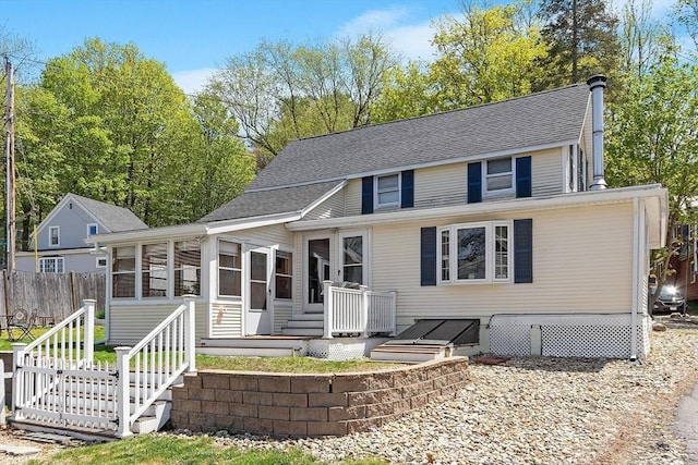 view of front of home featuring a sunroom, roof with shingles, fence, and a deck