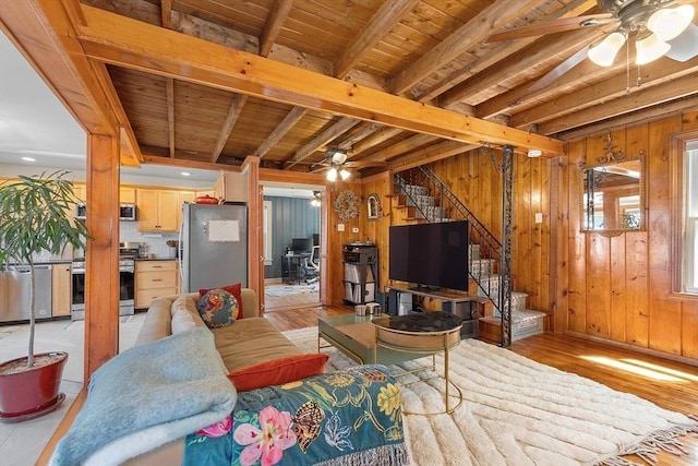 living area featuring stairway, wood walls, and a ceiling fan