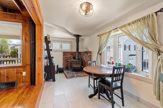 dining room featuring a wood stove, visible vents, and lofted ceiling