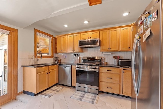 kitchen with a sink, stainless steel appliances, recessed lighting, light tile patterned floors, and dark countertops