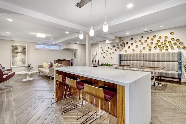 kitchen featuring pendant lighting, a kitchen island, light parquet floors, and a kitchen breakfast bar