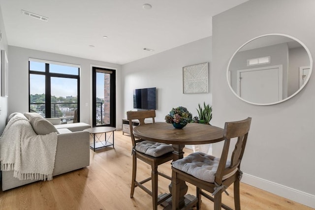 dining room featuring light wood-style flooring, visible vents, and baseboards