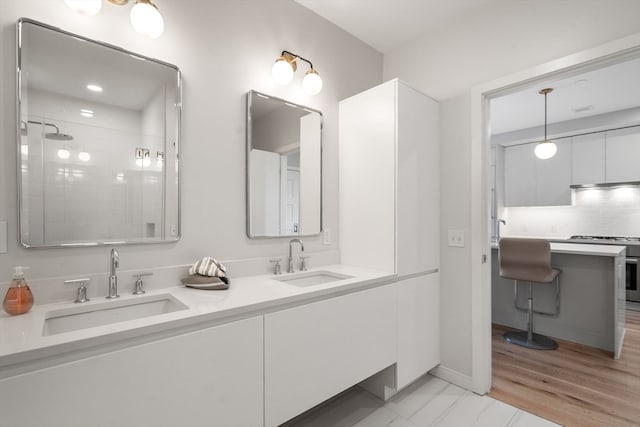 bathroom with vanity, hardwood / wood-style floors, walk in shower, and tasteful backsplash