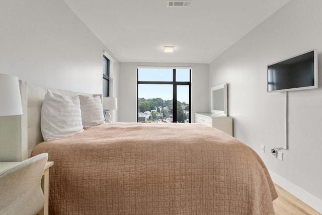 bedroom featuring baseboards, visible vents, and light wood-style floors