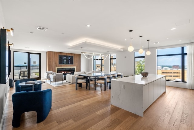 kitchen with light stone counters, light hardwood / wood-style flooring, decorative light fixtures, and a center island