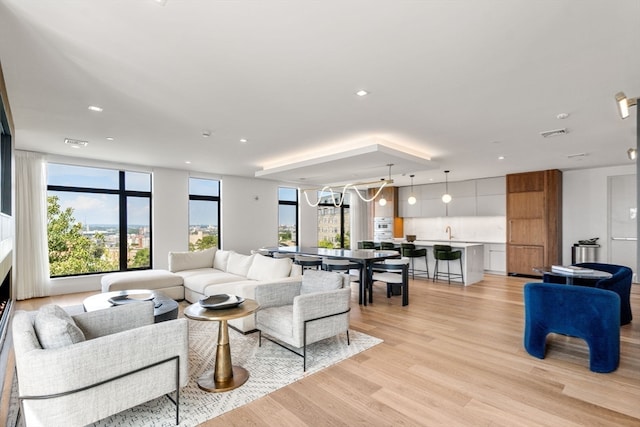 living room with light wood-type flooring, a wealth of natural light, and sink