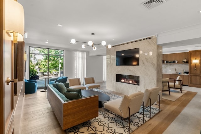 living room with a fireplace, light hardwood / wood-style floors, and a notable chandelier