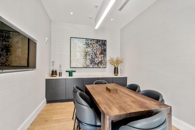 dining space with light wood-type flooring and baseboards