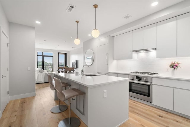 kitchen with light wood finished floors, visible vents, stainless steel appliances, and a sink