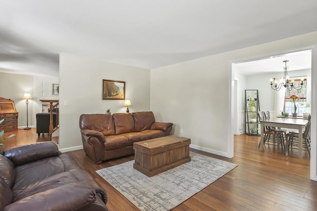 living room with baseboards, wood finished floors, and a notable chandelier