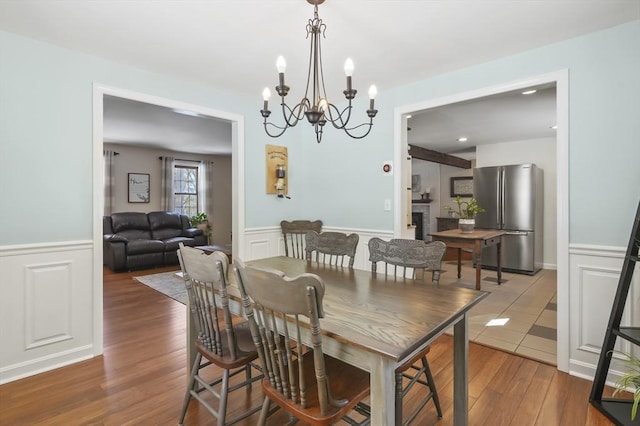 dining room featuring a wainscoted wall, a fireplace, wood finished floors, and a decorative wall